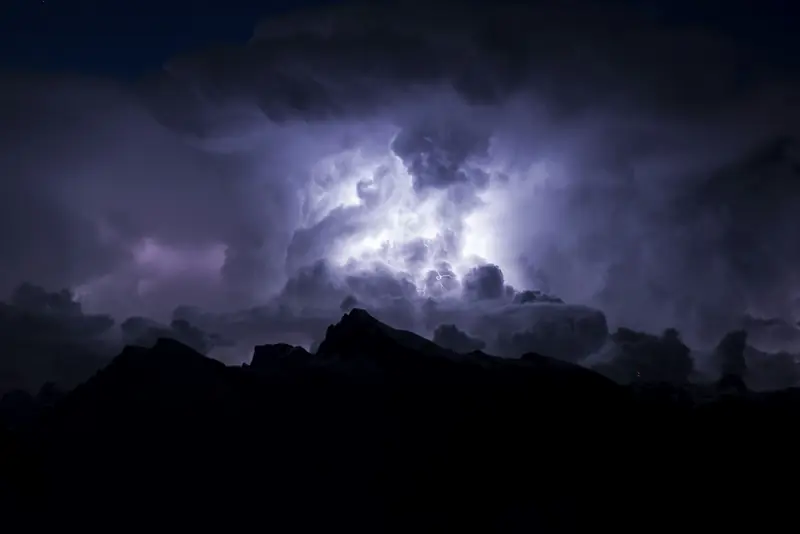 Lightning inside storm clouds at night